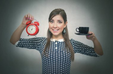 Kahve molası. Kahve zamanı. Öğle yemeği molası. Bir gri arka plan üzerinde izole saat ile bir fincan kahve ve kırmızı alarm clock elinde tutan mutlu gülümseyen kadın.