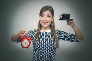 Kahve molası. Kahve zamanı. Öğle yemeği molası. Bir gri arka plan üzerinde izole saat ile bir fincan kahve ve kırmızı alarm clock elinde tutan mutlu gülümseyen kadın.