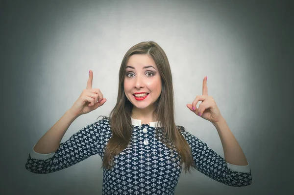 Mutlu unconcern kız onun işaret parmakları üzerinde kopya alanı tarafından kafasını ve gülümseyen izole üzerinde gri arka plan üzerinde görünüyor. Özel fırsat. Telefon numarası iletişim.