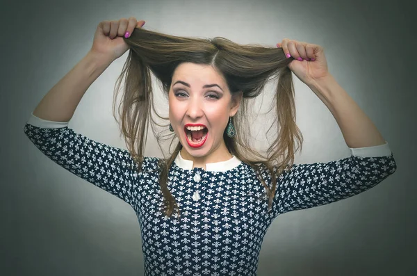 Şok sürpriz kadın saçlarını tarafından elleri üzerinde bir kafa tutuyor ve izole üzerinde gri arka planda çığlık atıyor. Aniden. Kazanmak.