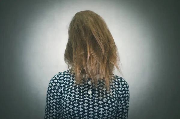 Rahatsız kadın yüzü gri arka plan üzerinde izole onun tüyleri arkasında gizler. Gizli. Meçhul kişi.