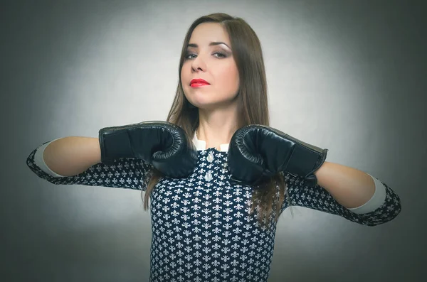 Confident and proud woman in boxing gloves beats herself in the chest isolated on gray backgroung. Smug bossy girl concept.