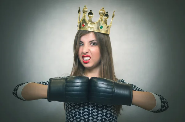 Angry confident woman with gold crown on her head and in a boxing gloves. Bossy girl in bad mood concept. Dissatisfied wife. Women Match. Women beauty contest concept. Female rivalry.