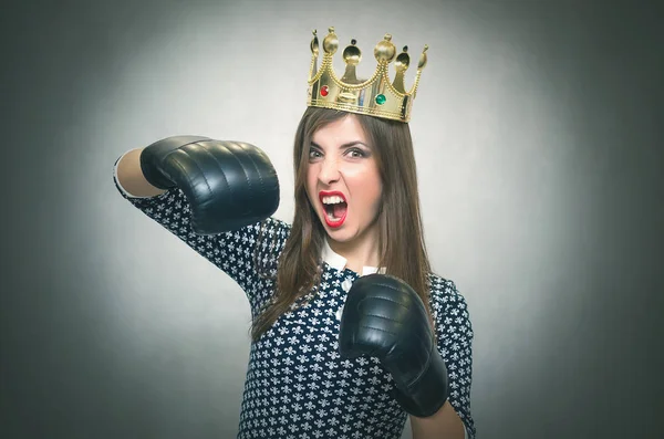 Altın taç başında ve boks eldivenleri ile kızgın kendine güvenen kadın. Kötü ruh kavramı ukala kız. Memnun karısı. Kadın maç. Kadın güzellik yarışması kavramı. Kadın rekabet.
