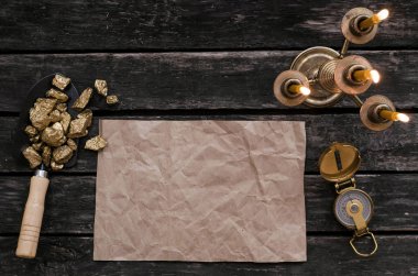Hazine harita, pusula ve kürek tam altın nuggets cevheri ahşap masa üzerinde kopya alanı olan boş kağıt sayfası. Hazine avcısı veya altın madenci kavramı.
