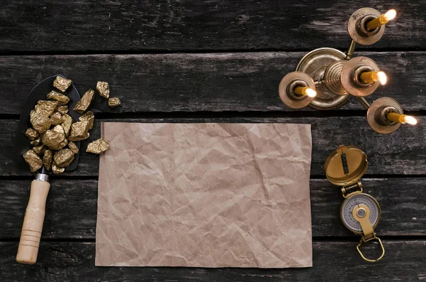 Hazine harita, pusula ve kürek tam altın nuggets cevheri ahşap masa üzerinde kopya alanı olan boş kağıt sayfası. Hazine avcısı veya altın madenci kavramı.