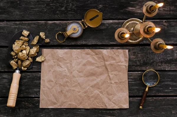 Hazine harita, pusula, Büyüteç'i büyüteç ve kürek tam altın nuggets cevheri ahşap masa üzerinde kopya alanı olan boş kağıt sayfası. Hazine avcısı veya altın madenci kavramı.