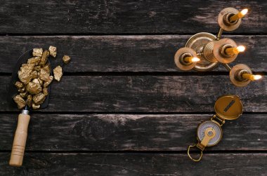 Altın cevheri nuggets kürek, pusula ve eski maceraperest tablo üzerinde yanan mum. Goldminer hazine avcısı kavramı.