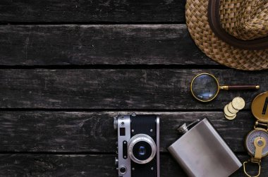 Maceracı tablo. Seyahat kavramı. Pusula, Büyüteç Camı, fotoğraf film kamera, cep şişesi, şapka ve eski ahşap masa arka plan kopya alanı ile para.