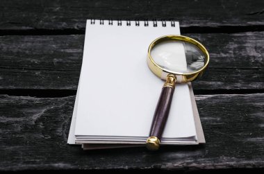 Büyüteç ve boş sayfa not etmek üstünde eski yaşlı ahşap arka plan masa.