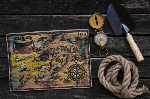 Treasure map, compass, shovel and rope on old wooden table background. Treasure hunter concept.