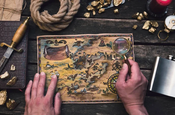 Treasure map in treasure hunter hands. Pirate man learning an old map with red mark.