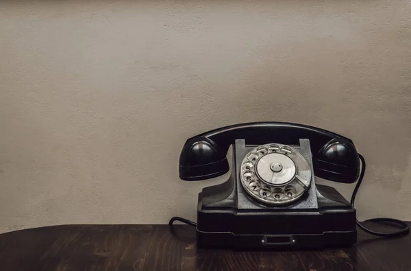 Retro rotary telephone on the table on wall background with copy space. Visiting card design.