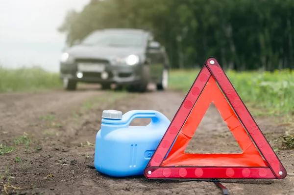 Benzin sınırı kavramı ulaştı. Yeterli yakıt. Kırmızı acil üçgen dur işareti, yakıt ve yolda araba için boş teneke kutu.