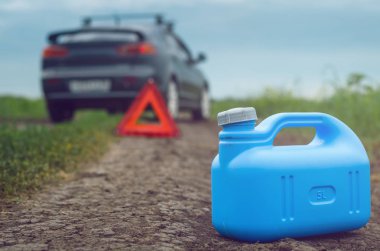 Benzin bitmiş kavramı. Yeterli yakıt. Kırmızı acil üçgen dur işareti, yakıt ve yolda araba için boş teneke kutu.
