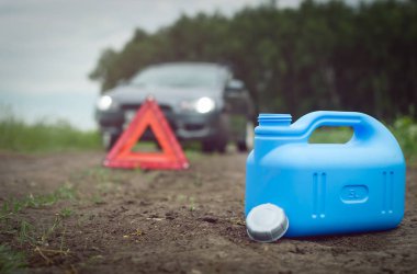 Yakıt bitmiş kavramı. Yeterli benzin. Kırmızı acil üçgen dur işareti, yakıt ve yolda araba için boş teneke kutu.