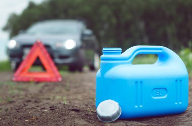 Yakıt bitmiş kavramı. Yeterli benzin. Kırmızı acil üçgen dur işareti, yakıt ve yolda araba için boş teneke kutu.
