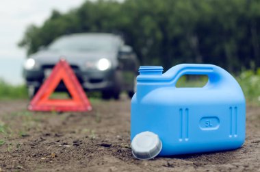 Yakıt bitmiş kavramı. Yeterli benzin. Kırmızı acil üçgen dur işareti, yakıt ve yolda araba için boş teneke kutu.