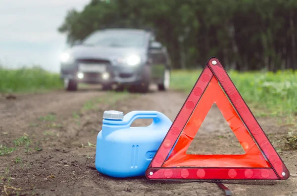 Yakıt bitmiş kavramı. Yeterli benzin. Kırmızı acil üçgen dur işareti, yakıt ve yolda araba için boş teneke kutu.