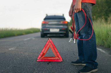 Düşük araba pil şarjı. Şarj edilmesi gerekir. Bir otomobil kablo starter ellerinde tutan sürücü.