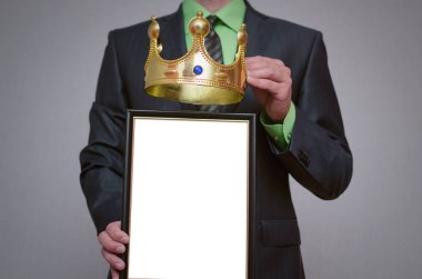 Kazanan boş diploma veya sertifika mockup işadamı elinde. Adam insan yüzü kopyalama yeri olan bir boş fotoğraf çerçevesi ve üstündeki altın bir taç tutuyor.