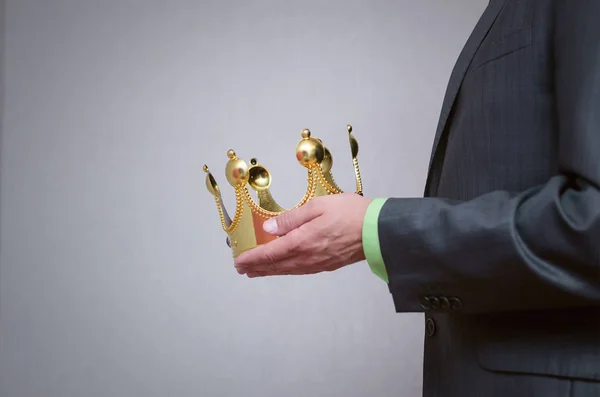 Businessman king holding in hands a gold crown and giving it to his assignee. Award ceremony concept. Winner.