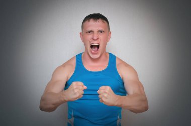 Öfkeli öfkeli vücut geliştirmeci adam gri arka plan üzerinde izole.