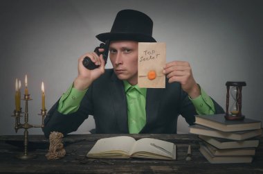 Melon adam elinde en iyi gizli belgelerle masaya oturuyor. Dedektif veya casus ajan veya polis müfettişi kavramı.
