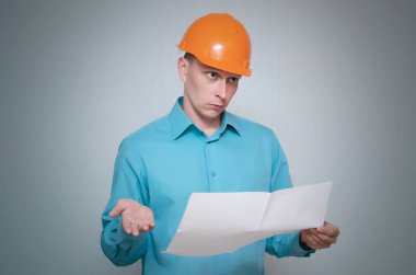 Karışık Oluşturucusu inşaat işçisi gri arka plan üzerinde izole bir planı taslağı belgesini elinde tutuyor.