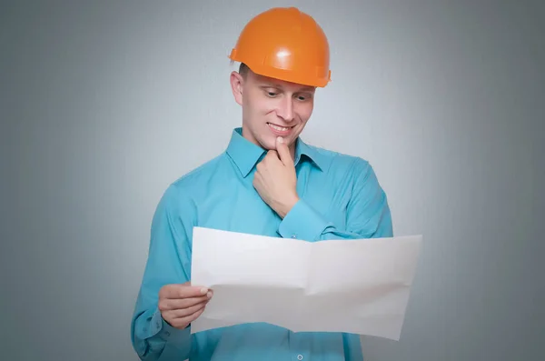 Glücklicher Bauarbeiter Hält Auf Grauem Hintergrund Einen Planentwurf Der Hand — Stockfoto