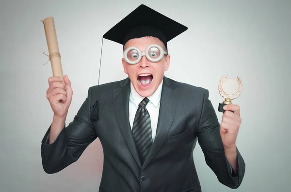 研究生在盖帽与文凭证书和金牌奖在手被隔绝在灰色背景 教育理念 — 图库照片