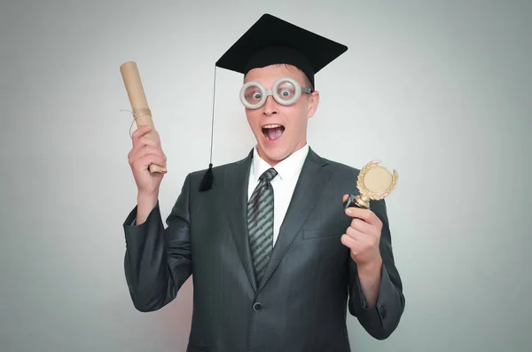 研究生在盖帽与文凭证书和金牌奖在手被隔绝在灰色背景 教育理念 — 图库照片