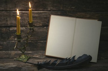Yanan mum ışığında boş boş sayfaları ile açık bir kitap. Yazar ya da yazar kavramı.