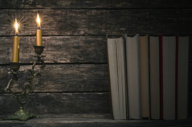 Yanan mum ışığında masada kitap yığını. Yazar ya da yazar kavramı. Okula dönüş.