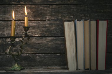 Yanan mum ışığında masada kitap yığını. Yazar ya da yazar kavramı. Okula dönüş.