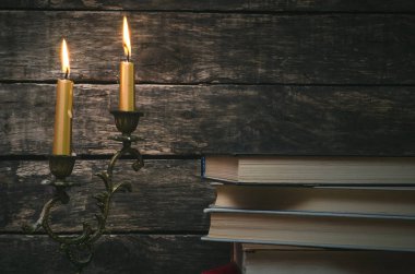 Yanan mum ışığında masada kitap yığını. Yazar ya da yazar kavramı. Okula dönüş.