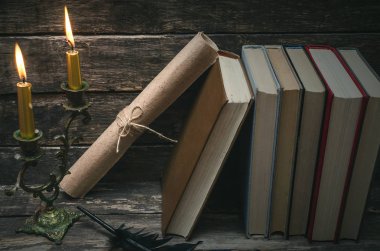 Yanan mum ışığında masada kitap yığını. Yazar ya da yazar kavramı. Okula dönüş.