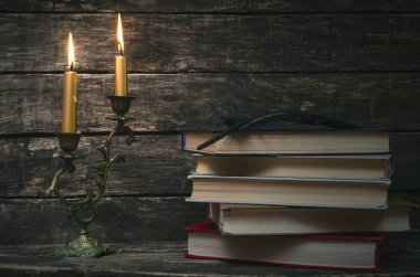 Yanan mum ışığında masada kitap yığını. Yazar ya da yazar kavramı. Okula dönüş.