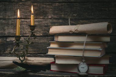 Yanan mum ışığında retro masasında kitap yığını. Yazar ya da yazar kavramı. Okula dönüş.