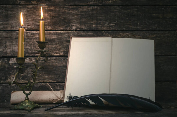 Open book with blank empty pages in the light of burning candle. Writer or author concept.