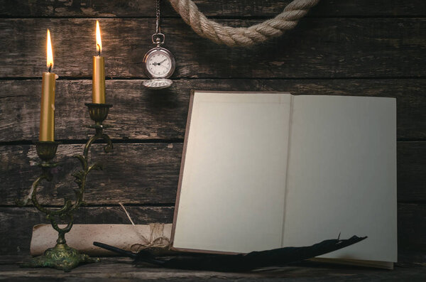 Open book with blank empty pages in the light of burning candle. Writer or author concept.