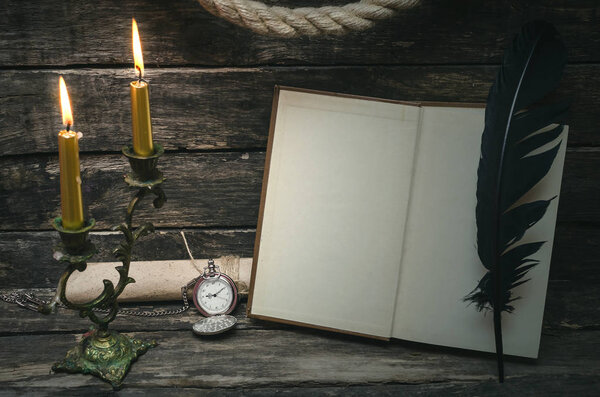 Open book with blank empty pages in the light of burning candle. Writer or author concept.