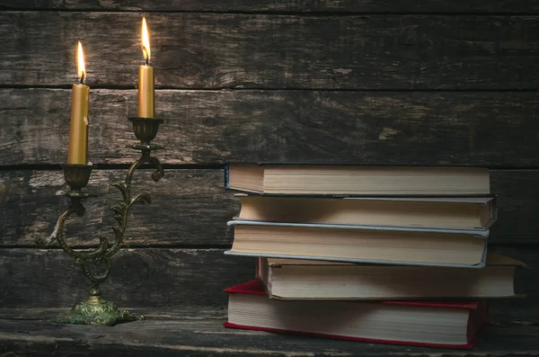 Yanan mum ışığında masada kitap yığını. Yazar ya da yazar kavramı. Okula dönüş.