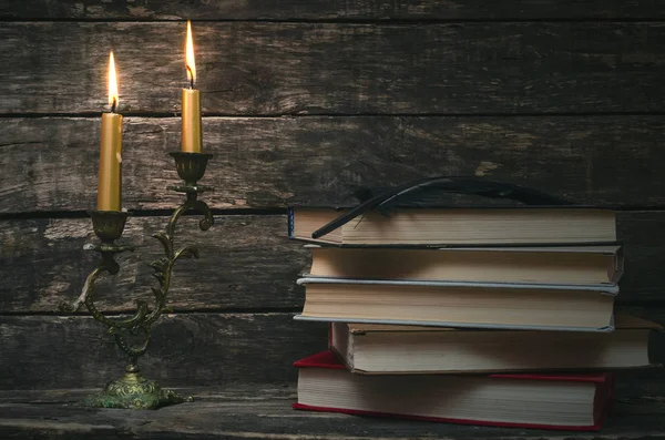 Yanan mum ışığında masada kitap yığını. Yazar ya da yazar kavramı. Okula dönüş.