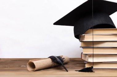 Kitap, lisansüstü kap, diploma ve fether kalem beyaz arka plan üzerinde izole okul masasında yığını.