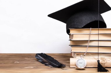 Kitapların yığını, kap, diploma ve cep İzle beyaz arka plan üzerinde izole okul masasında mezun.