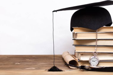 Kitapların yığını, kap, diploma ve cep İzle beyaz arka plan üzerinde izole okul masasında mezun.