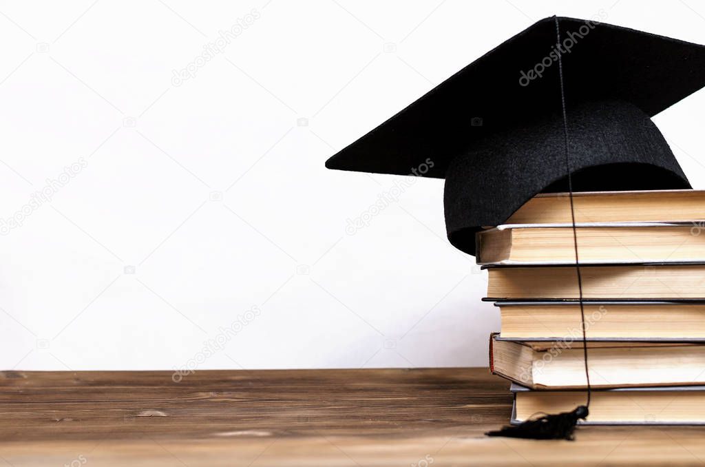 Stack of books and graduate cap on the school desk isolated on white background.