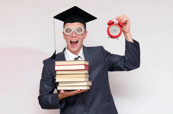 本と灰色の背景に分離された赤い目覚まし時計の大学院生 教育コンセプト — ストック写真