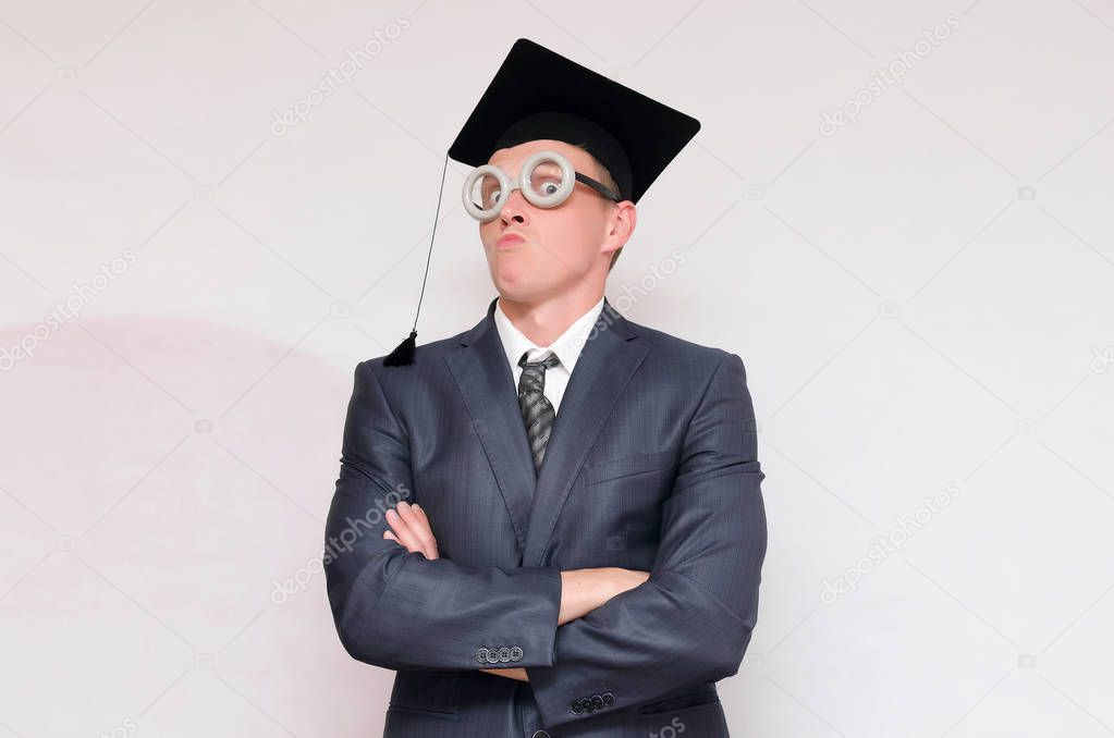 Disgruntled and arrogant graduate student in the cap isolated on gray background. Education concept.